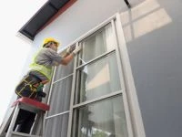 white man installing hurricane windows in florida standing on ladder